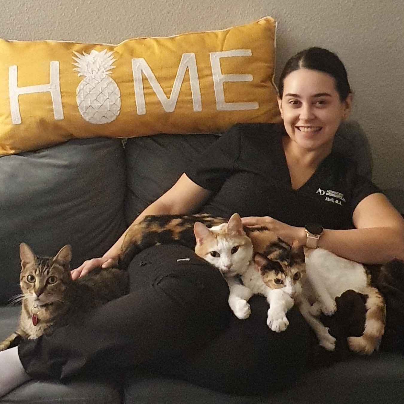 A woman sitting on a couch with three cats on her lap